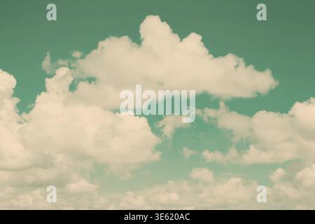 Soft, fluffy clouds float across a bright teal sky in a tranquil daytime setting. This clear sky evokes a sense of peace and invites relaxation and en Stock Photo