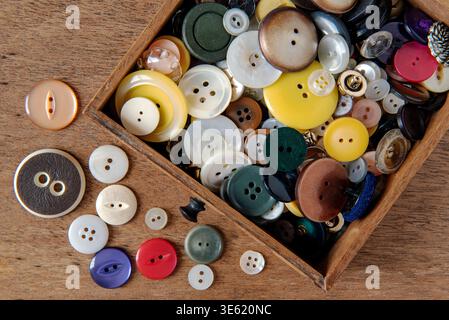 Mixed, vintage buttons in draw or box on wooden table. UK Stock Photo