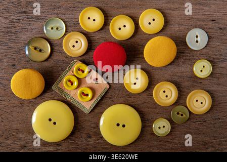 Vintage yellow sewing buttons with one red one in the centre on wooden tray Stock Photo