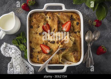 Food, Bread and butter pudding with raisins and fresh strawberry in white baking dish, top view Stock Photo