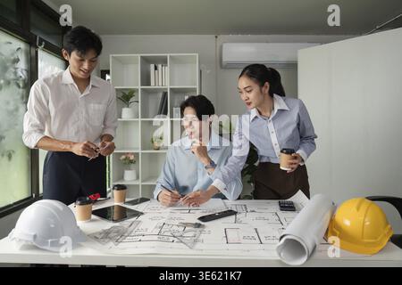 Three professionals collaborate on architectural designs and project plans, fostering teamwork and innovation in a modern workspace Stock Photo