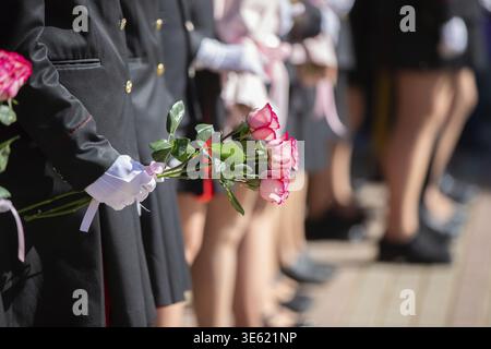 Hands in white gloves of an unrecognizable man in uniform holding a bouquet of roses Stock Photo