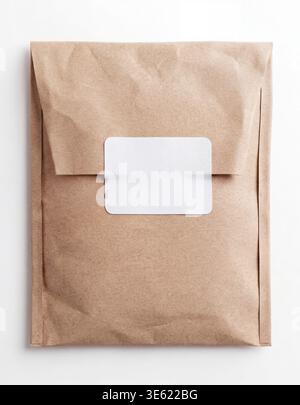Mockup of a brown kraft paper envelope sealed with a blank white rectangular sticker, top view. Stock Photo