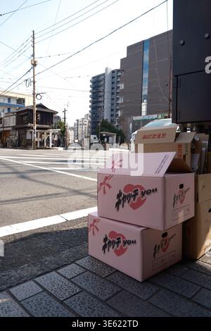 Pink cardboard boxes with romantic heart design on a Kumamoto street corner with traditional buildings Stock Photo