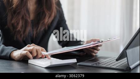 Woman with financial report and calculator. Woman using calculator to calculate report at the table in office Stock Photo
