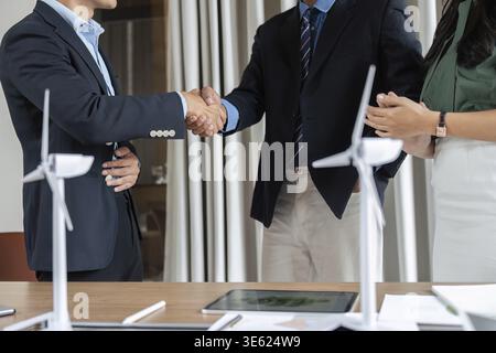 Two business professionals shaking hands in a meeting focused on ESG initiatives, highlighting their commitment to sustainability and collaboration Stock Photo