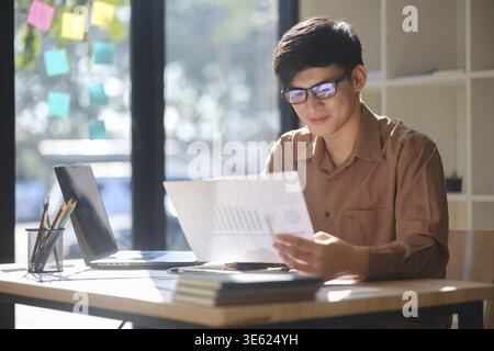 A young businessman analyzing financial data and trends for investment decisions. His focused expression reflects strategic thinking, business plannin Stock Photo