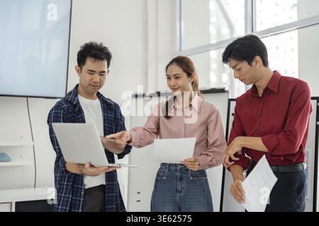 In a vibrant office setting, team members focus on new design trends as they analyze reports and visuals, demonstrating teamwork and a shared commitme Stock Photo