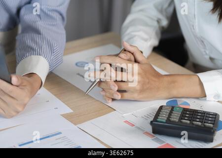 Two business professionals engaged in a financial discussion, analyzing reports and data with a calculator and documents Stock Photo