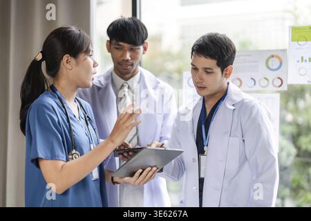 A group of healthcare professionals engage in a collaborative discussion, sharing insights on data and patient care in a modern medical facility Stock Photo
