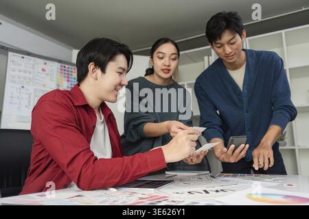 In a modern workspace, a diverse team collaborates on a design task, showing charts and digital displays while sharing valuable insights and ideas Stock Photo