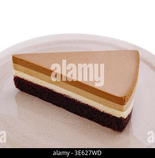 Food, A slice of a delectable three-layer cake rests on a light plate. The layers feature rich chocolate, vanilla mousse, and a chocolate base, showca Stock Photo