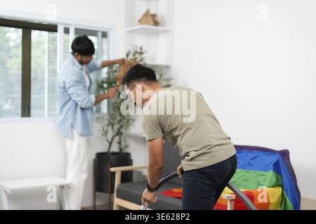 Young men collaborating on home cleaning tasks, showcasing teamwork and friendship in a bright, welcoming environment Stock Photo