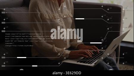 Working woman typing on silver laptop at home on dark sofa, wearing dotted blouse, showing overlays Stock Photo