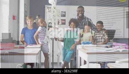 Gathering teacher in plaid shirt guiding students examining skeleton model in classroom with notes Stock Photo