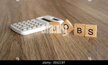 Jobs word on wooden blocks next to a white calculator. Stock Photo