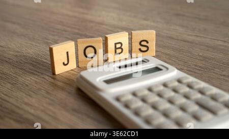 Jobs word on wooden blocks next to a white calculator. Stock Photo