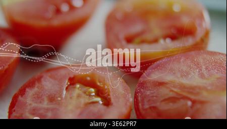 Displaying cut ripe red tomatoes resting on pale tray in kitchen showing seeds juice dotted overlay Stock Photo