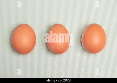Three raw brown chicken eggs top view on blue green background Stock Photo