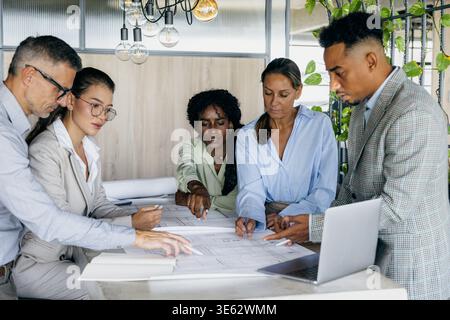 Black structural engineer explaining technical details to white and asian Stock Photo
