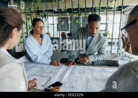Multiracial architects examining construction plans together Stock Photo
