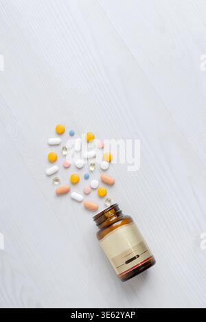 Open medicine bottle with mixed pills scattered on clean background, healthcare and pharmaceutical concept Stock Photo