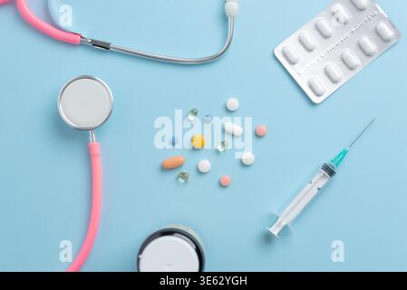 Medical flat lay with stethoscope, syringe and colorful pills on blue background, healthcare and treatment concept Stock Photo
