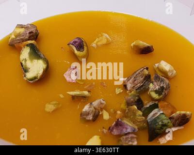 Close-up view of a bowl of vibrant orange soup, likely pumpkin, butternut squash, or carrot based, with a smooth and velvety texture. The soup is Stock Photo