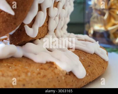 Extreme close-up macro photograph of gingerbread house construction showing textured brown gingerbread cookie pieces joined together with thick white Stock Photo