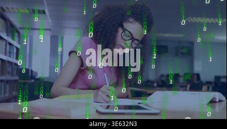 Writing woman wearing pink top and black glasses leaning over notes at library, tablet binary code Stock Photo