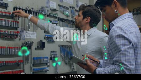 Reaching two techs wearing button shirts selecting sockets on pegboard with tablet and AR overlays Stock Photo