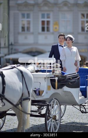 Bride and groom standing in a white horse-drawn carriage on a cobblestone square in Old town of Prague, Czech Republic on 12 August 2024 Stock Photo