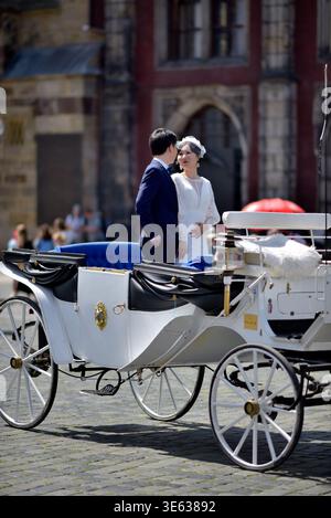 Bride and groom standing in a white horse-drawn carriage on a cobblestone square in Old town of Prague, Czech Republic on 12 August 2024 Stock Photo