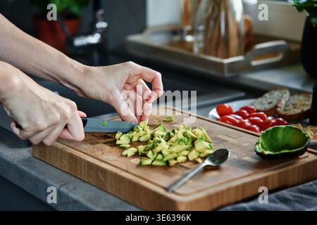 Process of chopping avocado for toasts. Woman preparing healthy breakfast at morning. Vegan food Stock Photo