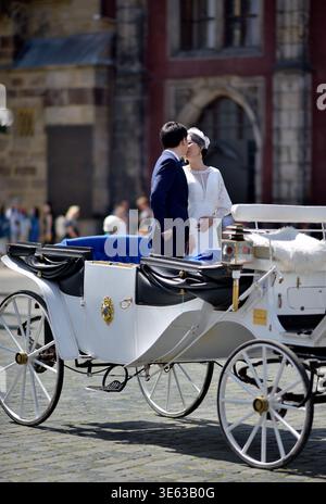 Bride and groom standing in a white horse-drawn carriage on a cobblestone square in Old town of Prague, Czech Republic on 12 August 2024 Stock Photo