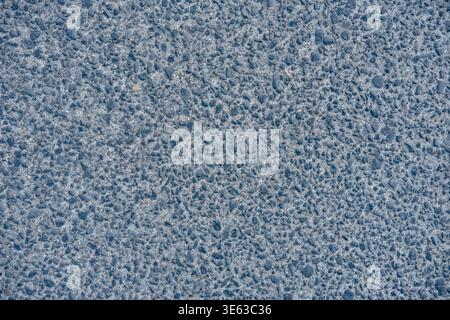 Grey asphalt surface with visible aggregate stones is shown as a road texture background Stock Photo