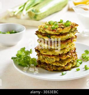 Stack of zucchini fritters. Vegetable vegetarian zucchini pancakes on plate on light background. Close up view Stock Photo