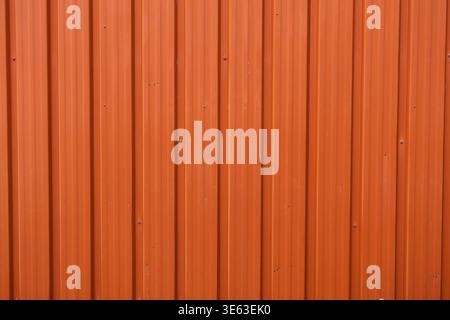 A close-up of a modern orange corrugated metal wall on a building exterior. Professional profile steel texture with vertical lines, ideal for architec Stock Photo