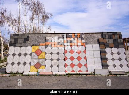 Wall of assorted paving stones and bricks, arranged in patterns. Colors range from gray to red and yellow. Ideal for construction, design, or urban pl Stock Photo