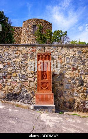 Ancient stone wall with carved wooden door. Towering stone structure under bright blue sky. Weathered textures and rustic charm. Ideal for historical Stock Photo