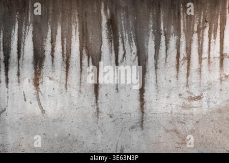 Weathered concrete wall displaying vertical water stains and drip patterns, creating a textured grungy appearance. Stock Photo