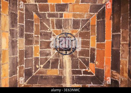 Aerial view of ancient stone courtyard with geometric patterns. Center features circular design with faded symbols. Warm tones highlight textured bric Stock Photo
