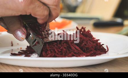 Hand grating red beet for healthy salad preparations on white plate Stock Photo