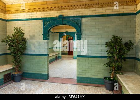 Tiled interior of Victoria Baths, Manchester, showing glazed green and cream tiles, arched doorway and terrazzo floor. Stock Photo