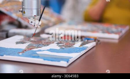 Robot arm holding a paintbrush creating an abstract artwork, exploring AI creativity Stock Photo