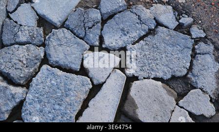 Broken asphalt pieces on the ground creating a distressed road texture background Stock Photo