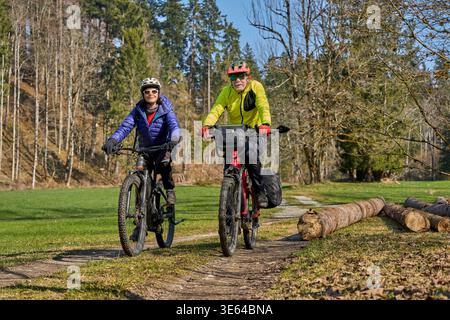 active senior couple cycling and having fun on a forest trail in the Allgaeu Alps, Germany Stock Photo