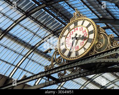 Old fashioned analogue railway station clock inside King's Cross train station showing the time in Roman numerals, London, UK Stock Photo