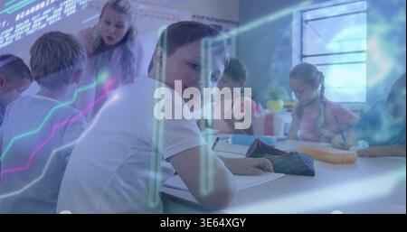 Smiling boy in white short-sleeve shirt holding pencil at desk in classroom, with open notebook Stock Photo