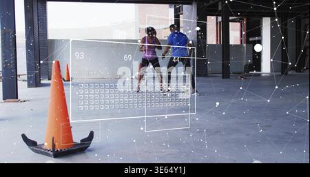 Holding pair of adults training in parking deck, in athletic wear, orange cone and data overlay Stock Photo